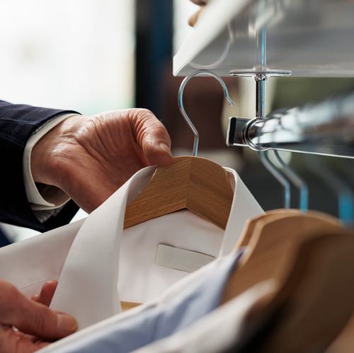 Senior man looking hangers filled with trendy shirts buying fashionable clothes modern boutique elderly customer shopping formal wear clothing store commercial activity close up shot